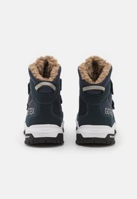 Blaue GORE-TEX Stiefeletten mit weichem, tanfarbigen Futter, Klettverschlussriemen und strukturierten Gummisohlen. Weiße Zwischensohle mit Markenlogo.