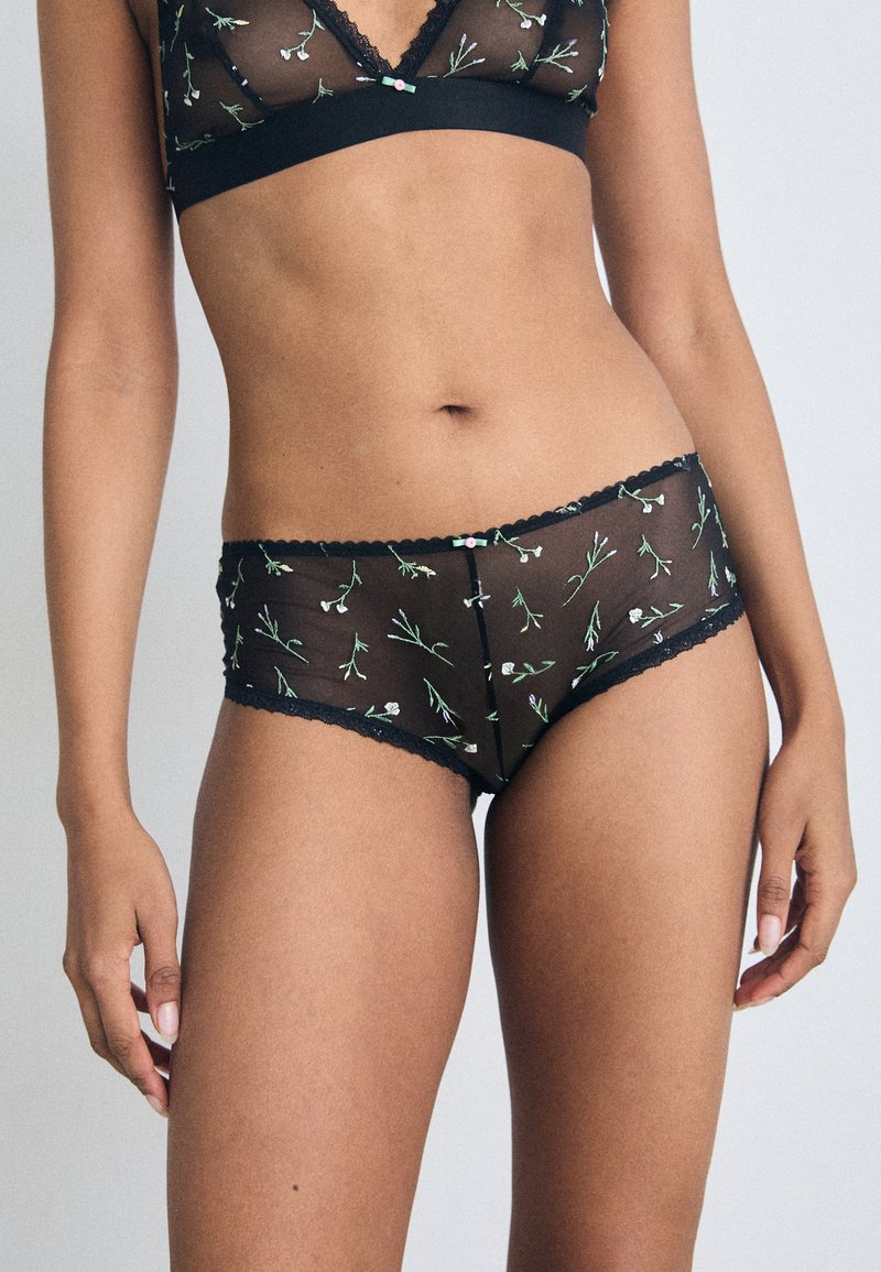 Zwart doorschijnend lingeriesetje met bloemenborduursels in wit en groen, afgewerkt met kantdetails en een comfortabele pasvorm.