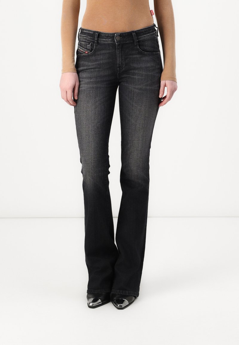 Jeans neri a campana realizzati in denim, con cinque tasche, cuciture a contrasto e una chiusura con zip e bottone. Texture liscia.