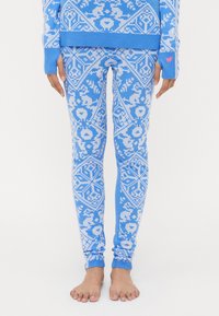 Strikket blå genser og leggings med et hvitt blomster- og geometrisk mønster. Ribbestrikkede mansjetter og ankelkanter gir tekstur og passform.