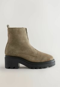 Khaki suède pahklipp, millel on paks must kummitald. Omab külgzipperit ja keeratavat silmust kanna peal. Sile tekstuur ja terav nin.