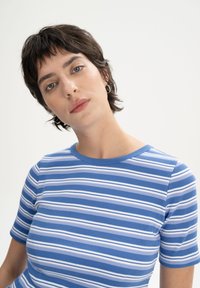 Striped t-shirt in blue and white, featuring a ribbed texture, short sleeves, and a round neckline.