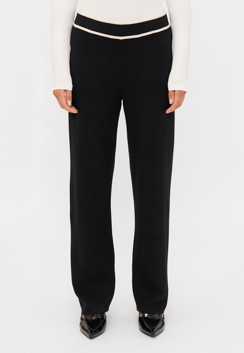 Černé kalhoty rovného střihu s vysokým pasem a kontrastním bílým lemem. Vyrobeny z měkké, elastické tkaniny.