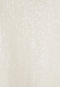 Tessuto con paillettes di colore bianco sporco, caratterizzato da piccole paillettes rotonde uniformemente distribuite, con una texture verticale e una leggera lucentezza.