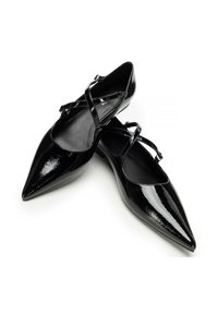 Scarpe in vernice nera con punte appuntite, cinturini alla caviglia e una superficie liscia, dotate di un tacco basso e un design minimalista.