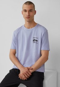 Hellblaue Baumwoll-T-Shirt mit kurzen Ärmeln, rundem Ausschnitt und schwarzem grafischem Text sowie Illustration im linken Brustbereich.