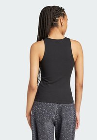 Čierny rebrovaný tielko s priliehavým strihom a bezrukávovým dizajnom, kombinované so sivými nohavicami s jemným potlačením leopardieho vzoru.