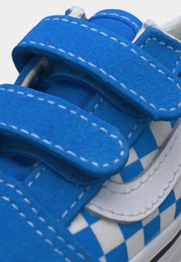 Μπλε και λευκό αθλητικό παπούτσι με σχέδιο καρό και δύο μπλε λουράκια βέλκρο με λευκό ράψιμο.