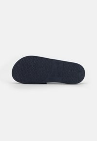 Sole in gomma navy con motivo testurizzato, caratterizzata da forme esagonali e dettagli di branding. Finitura liscia, design ergonomico.