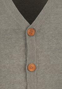 Cardigan grigio con scollatura a V, dotato di due bottoni in legno al centro. Il tessuto ha una consistenza morbida con bordi a coste.