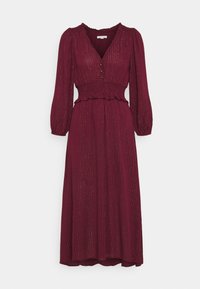 Robe bordeaux avec un décolleté en V, des manches longues bouffantes, une taille smockée et un ourlet festonné. Elle présente de subtils détails en fil métallique.