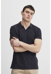 Polo shirt in dark navy, short sleeves, featuring a collared neckline and a small logo on the chest. Smooth cotton fabric with a classic fit.