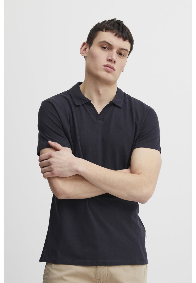 Polo shirt in dark navy, short sleeves, featuring a collared neckline and a small logo on the chest. Smooth cotton fabric with a classic fit.