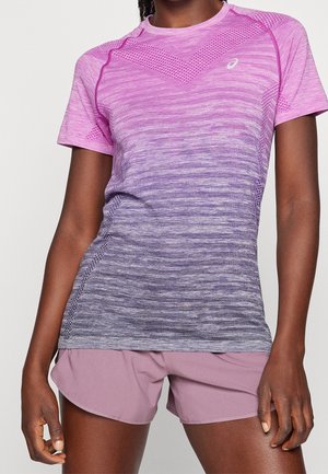 Athlet trägt ein lila Ombre-Kurzarm-Sportshirt mit Mesh-Details und helllila Sportshorts, steht vor einem einfarbigen Hintergrund.