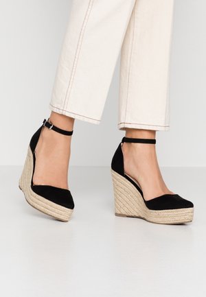 Czarne zamszowe buty na koturnie z plecioną podeszwą espadrylową, z paskiem na kostkę i okrągłym noskiem.