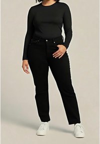 Top negro de manga larga combinado con jeans negros de tiro alto y zapatillas blancas. Los jeans tienen un diseño clásico de cinco bolsillos y un ligero elastano.