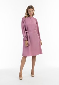 Šaty fit-and-flare z měkké růžové tkaniny, s kulatým výstřihem, dlouhými rukávy s nabíranými manžetami a opaskem na mašličku.