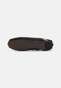 Musthave mustruud mustärka kingadega, millel on ümar nina, kollane aksent ja dekoratiivne mustriga riistvara ülemisel osal. Paindlik must tald.