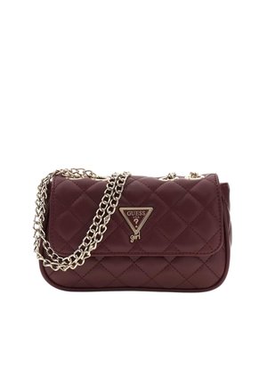 Sac à main matelassé Guess marron foncé avec plaque logo triangulaire dorée et bandoulière chaîne dorée sur fond blanc.