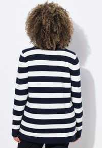 Marinblå och vit randig tröja med texturerad stickning, med avslappnad passform och sprund i nederkant. Bakvy, långa ärmar.