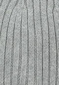 Szary, dziany beanie z prążkowaną fakturą i pionowymi paskami. Wykonany z miękkiej przędzy, ma delikatne różnice w grubości.