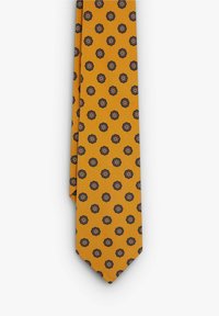 Corbata amarilla con un patrón floral repetitivo en negro y rojo con acentos en azul, hecha de una tela suave.