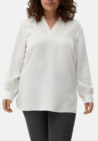 Witte blouse met een V-hals, lange opgezette mouwen die bij de boorden gerimpeld zijn, een ontspannen pasvorm en een zachte, lichte stof.