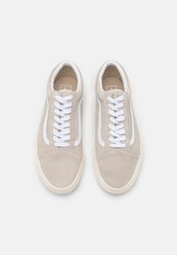 Beige suede sneakers with white laces, a white side stripe, and a textured upper. Features a cream rubber sole and round toe design.