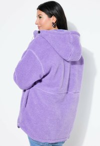 Lila Fleece-Hoodie mit weicher Textur, mit einem Kordelzug am Ausschnitt und Seitentaschen. Lockere Passform, knielanger Schnitt.