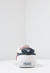 Sneaker in tela bianca con un accento in pelle blu navy sul tallone e un dettaglio laterale rosso. Caratterizzata da una suola in gomma e dal marchio Gola sul tallone.
