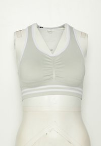 Sutiã desportivo verde claro com detalhes em branco, apresentando um centro franzido, design em V e riscas horizontais na parte inferior.