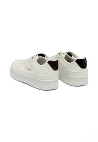 White sneakers with a smooth leather-like exterior, thick rubber sole, and distinct black textured accents on the heel. Brand logo on the side.