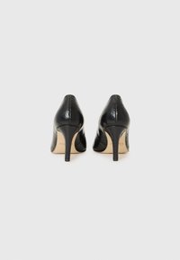 Scarpe nere con tacco alto caratterizzate da una texture a motivo serpente. Presentano una punta affusolata e un tacco sottile a stiletto. Rivestimento interno liscio.