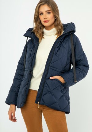 Marineblauwe gewatteerde pufferjas met een capuchon, een ritssluiting aan de voorkant en een trekkoord. Bevat zijzakken en een geweven stofontwerp.