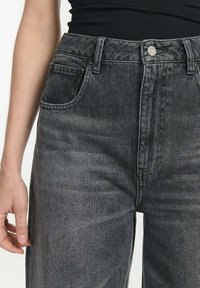 Hoge taille zwarte denim jeans met een vervaagde wassing, voorzien van een knoopsluiting aan de voorkant, riemlussen en zijzakken. Glad textuur.