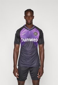 Μωβ και μαύρη φανέλα ποδοσφαίρου με κοντά μανίκια, με λαιμόκοψη σε σχήμα V, λογότυπο «Sunweb» και ανοιχτές διαγώνιες ρίγες στο μπροστινό μέρος.