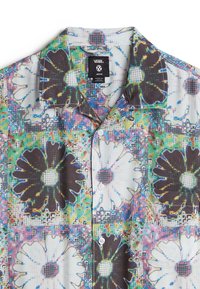 Camicia a maniche corte con un motivo floreale in tonalità bianche e scure, con una sovrapposizione di griglia testurizzata, chiusura a bottoni e colori vivaci.