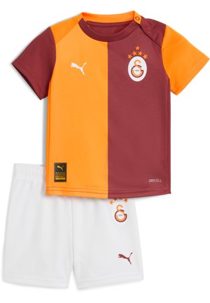Børns kortærmede fodboldtrøje med halv orange, halv bordeaux skjorte og hvide shorts, med Puma-logoer og holdemblem.