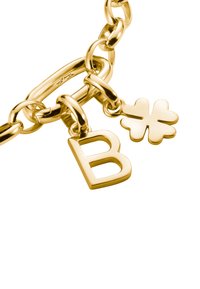 Goldfarbene Kettenarmband mit einem großen Buchstaben "B" und einem vierblättrigen Kleeblatt-Anhänger. Glatte Textur mit glänzendem Finish.
