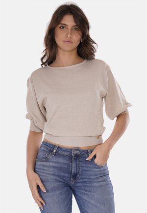 Maglione beige corto in un morbido tessuto a maglia testurizzata, con scollo rotondo e maniche corte a sbuffo, abbinato a jeans blu.