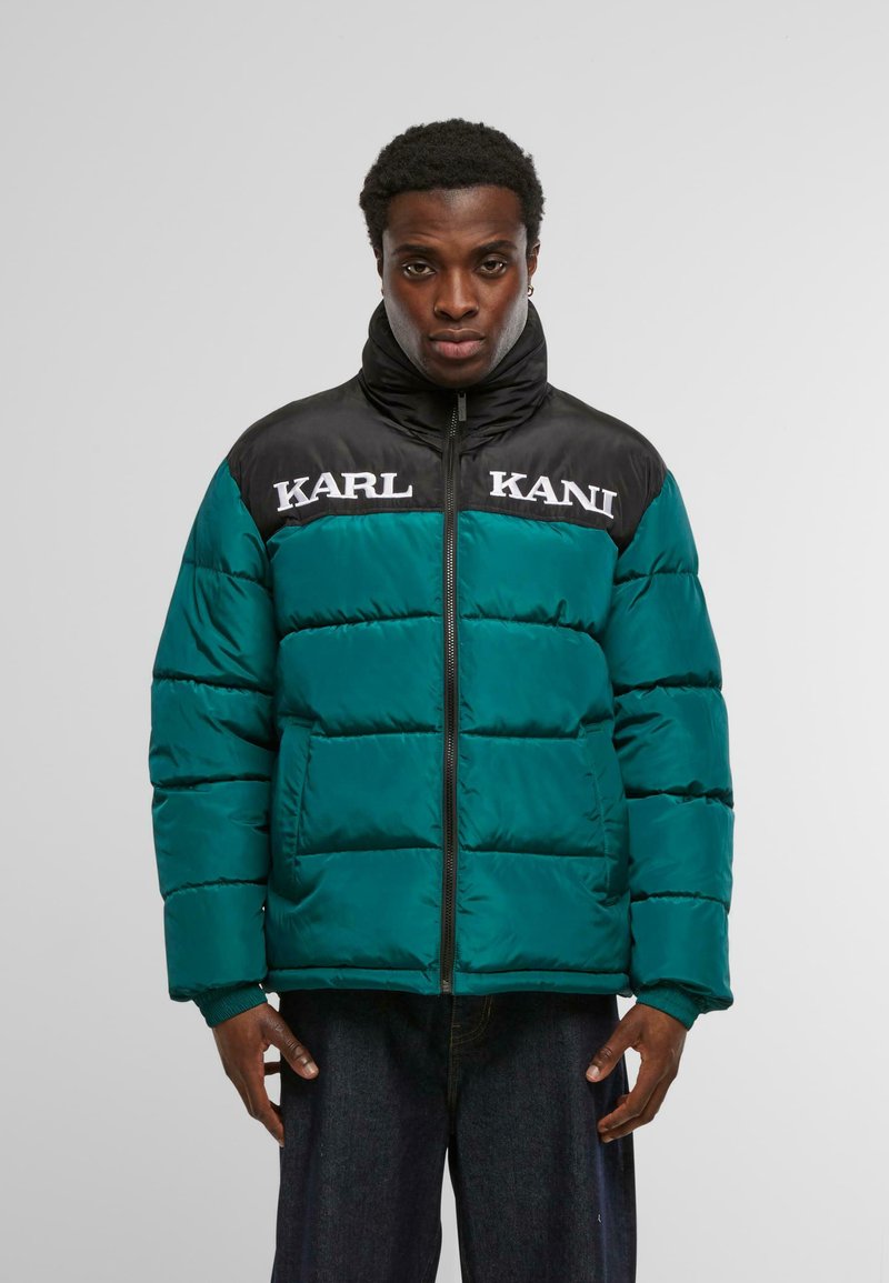 Pikowana kurtka w kolorze zielonkawoniebieskim z czarnym karczkiem na ramionach, zapinana na zamek z przodu, z białym napisem "KARL KANI" na piersi. Ściągacze na mankietach i pikowana faktura.
