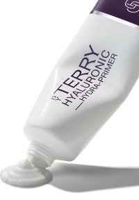 Witte knijptube van By Terry Hyaluronic Hydra-Primer met paarse tekst. Glad, romig primer die uit de nozzle komt, op een witte achtergrond.