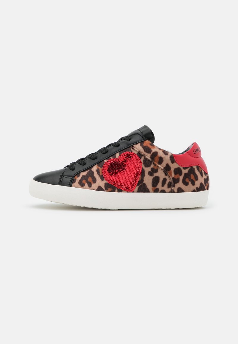Baskets basses avec imprimé léopard, bout et lacets noirs, semelle blanche, languette de talon rouge, et cœur rouge en sequins sur le côté.