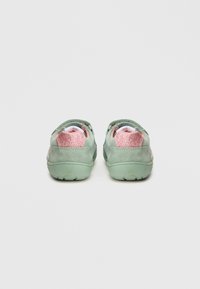 Light green suede shoes with pink glitter accents on the heel, rounded back, and textured rubber sole for grip.