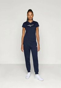 Σκούρο μπλε σετ ρουχισμού που περιλαμβάνει κοντομάνικο μπλουζάκι με λευκό λογότυπο και παντελόνι φόρμας. Το υλικό φαίνεται μαλακό, κατάλληλο για καθημερινή χρήση.