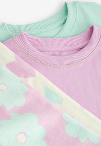 Trois sweatshirts à col rond en vert menthe, rose doux et crème, avec des encolures côtelées et un motif floral sur le rose.