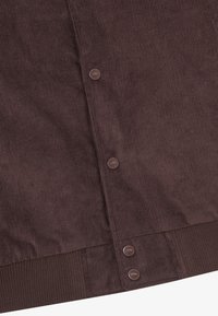 Brown corduroy fabric with vertical stripes, featuring bronze buttons along the seam and a ribbed band at the bottom.