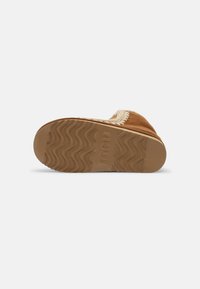 Pantofole in suede marrone con rivestimento morbido, suola in gomma testurizzata e motivo a onde per una migliore aderenza. Presentano dettagli cuciti lungo il bordo.