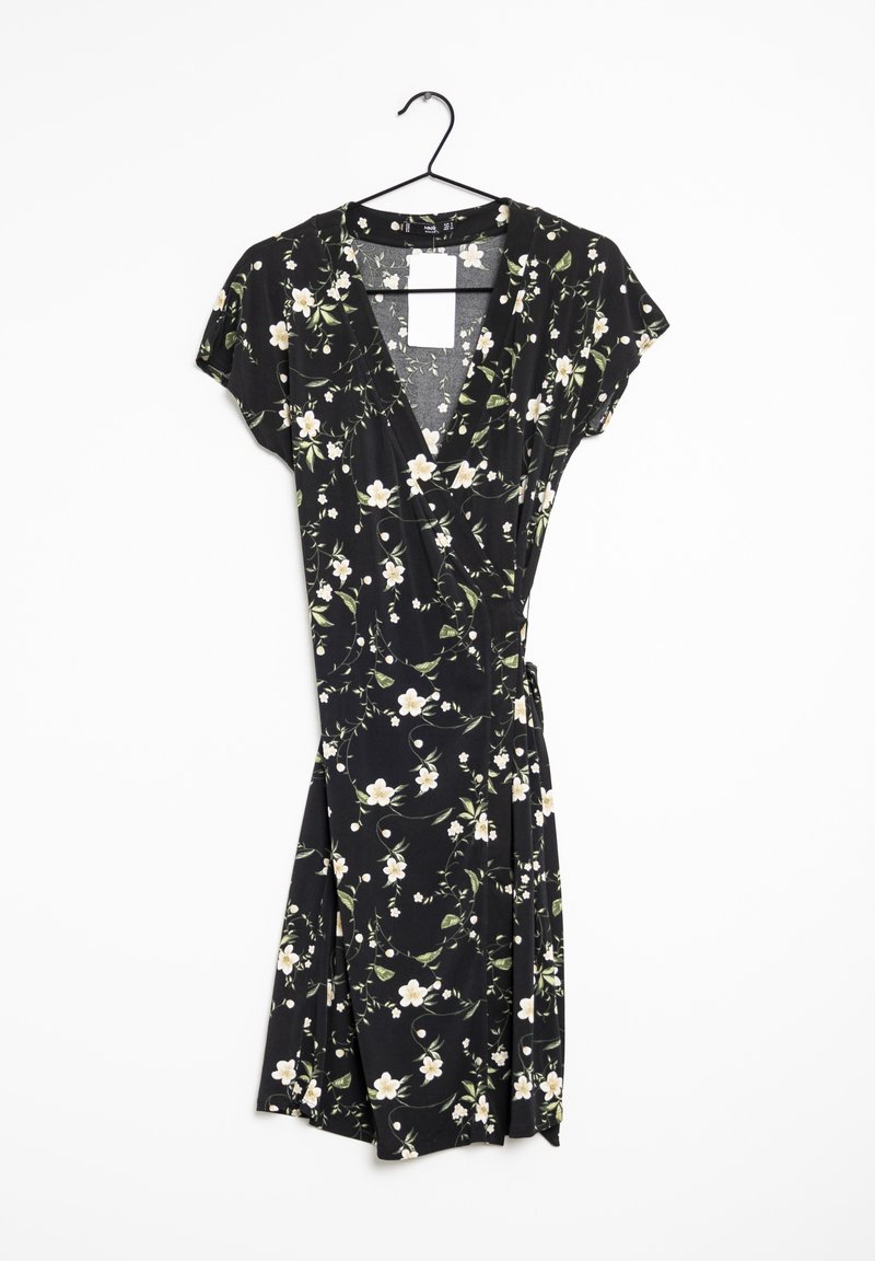 Robe portefeuille noire à manches courtes avec motif floral blanc et vert suspendue sur un cintre noir sur fond blanc.