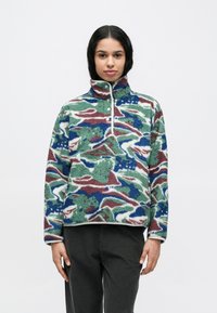 Φλις μπλούζα σε πράσινο, μπλε και μαρουνοκόκκινο με αφηρημένο μοτίβο, με ψηλό γιακά, άνοιγμα με μισό φερμουάρ και λευκή επένδυση. Υλικό με υφή, ζεστό.